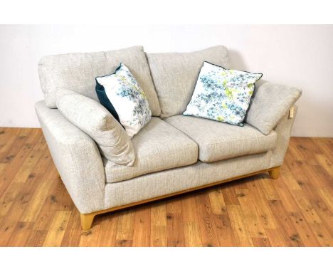 A contemporary Ercol Novara two-seater sofa, the cushioned seat and backrest with shaped armrests with side cushions, raised 