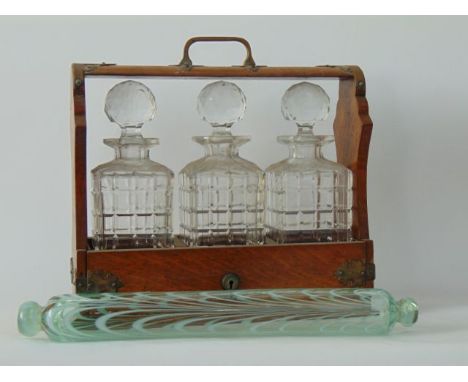 An early 20th century oak and brass mounted tantalus containing three cut glass decanters and stoppers of square cut form tog