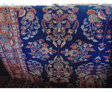 A substantial wool work carpet with deep blue ground decorated in concentric floral medallions and motifs in shades of pink, 