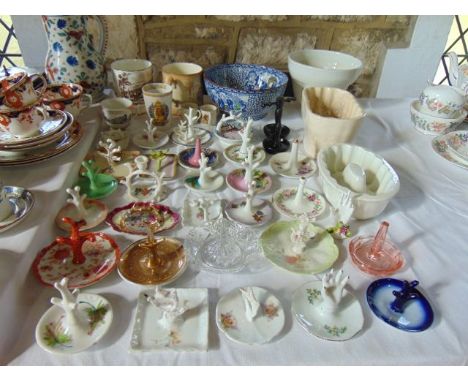 A collection of ceramic and other ring stands of various designs including floral decorated examples, examples in the form of