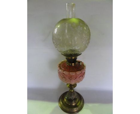 A Victorian oil lamp raised on a brass stem with fluted and further embossed detail leading to a pink opaque moulded glass fo