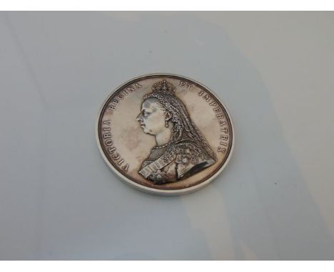 A heavy white metal Victorian commemorative medal with relief profile portrait of The Queen to one side and the enthroned Que