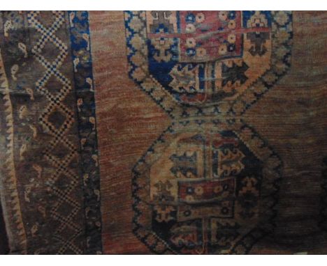 A substantial wool carpet in the Persian manner set within a pale brown field with extensive medallion detail in shades of de