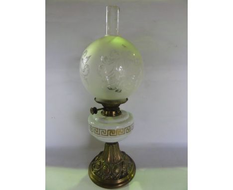 A Victorian oil lamp raised on an embossed brass foot supporting an opaque glass fount with Greek Key gilded border, supporti