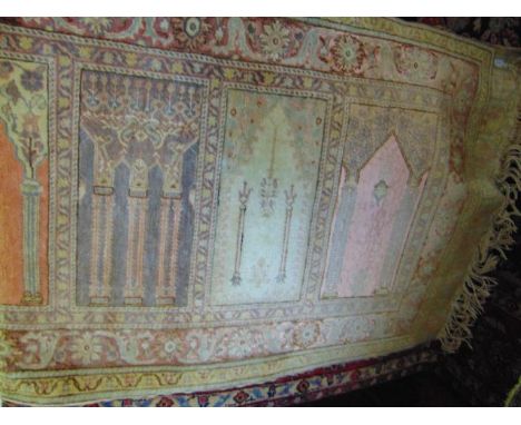 A fringed wool work runner with central panels detailing architectural decoration in shades of pink, brick red and cream, etc