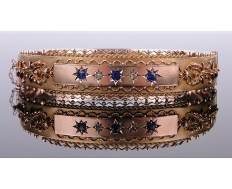 An Edwardian 9ct gold blue and white stone set hinged bangle,
with filigree decoration, 12.5g.