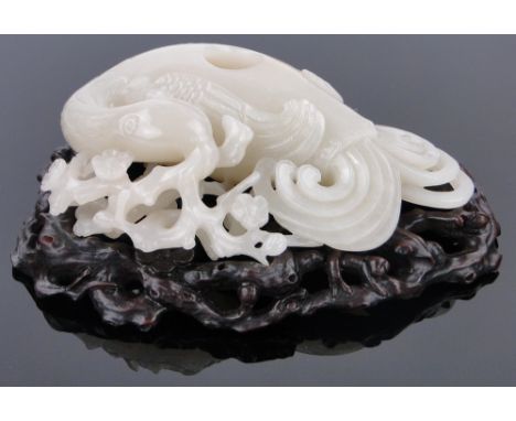 A Chinese relief-carved jade brush washer modelled as a phoenix,
on carved wood stand, length 5.5" overall.