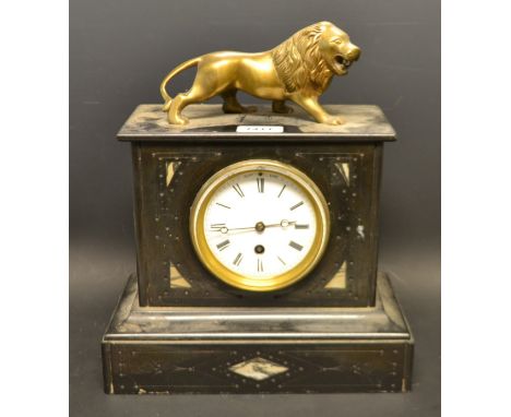 A late 19th century French black slate mantel clock, inlaid with marble lozenges, surmounted with a gilt brass naïve roaring 