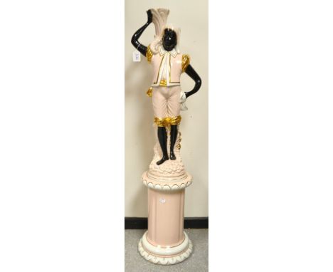 A ceramic blackamore figure on a pedestal in salmon and gilt.