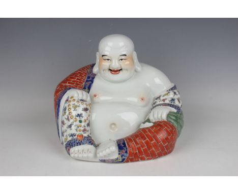 A Chinese famille rose porcelain figure of a seated smiling Buddha, early 20th century, modelled wearing an open floral decor