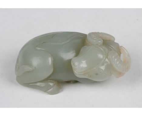 A Chinese pale celadon jade carving of a water buffalo, modelled in a recumbent pose with head turned to its right, length 6.
