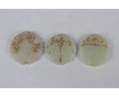 A group of three Chinese pale celadon jade circular plaque pendants, probably 20th century or later, each of carved and pierc