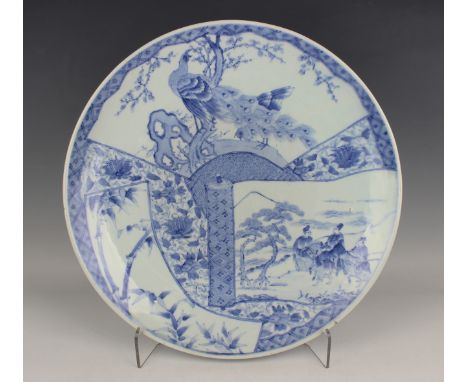 A Japanese Arita blue and white porcelain circular charger, Meiji period, painted with two peacocks in a fan shaped panel, fi