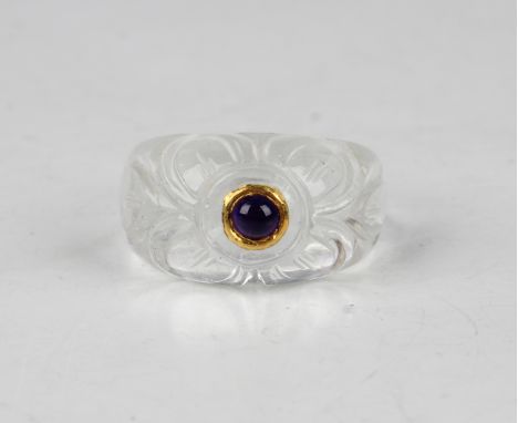 An Indian rock crystal ring, the front carved with a foliate design centred with a cabochon amethyst, length 3.2cm.Buyer’s Pr
