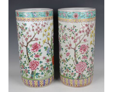 A pair of Chinese famille rose porcelain stick stands, 20th century, each cylindrical body painted with peony and prunus, hei