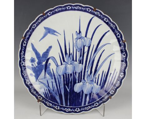 A Japanese Arita blue and white porcelain circular dish, Meiji period, painted with a bird flying above irises within a bambo