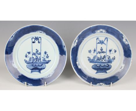 A pair of Chinese blue and white porcelain plates, Kangxi period, each painted with a flower basket within prunus rim, underg