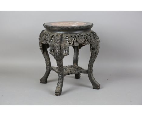 A Chinese hardwood stand, late Qing dynasty, the circular top inset with a rouge marble panel within a carved beaded border, 