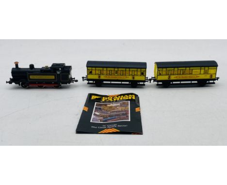 An unboxed Graham Farish N gauge "The Shredded Wheat Co" steam locomotive in black livery, with two matching passenger coache