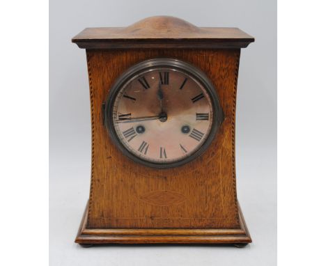 An Arts and Crafts oak mantel clock, with inlaid detailing, raised on flattened bun feet - with key