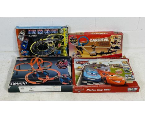 A boxed Ideal made Mask Motorized Daredevil track set, along with three other racing set including DIsney Pixar Cars Piston C