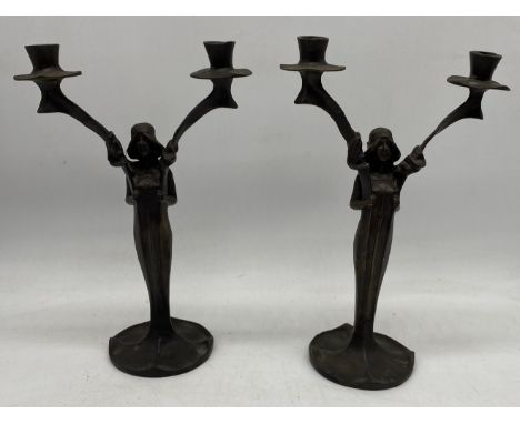 A pair of bronze Art Nouveau candlesticks of women holding two candle branches, both bearing the signature J. Moigniez 1902, 
