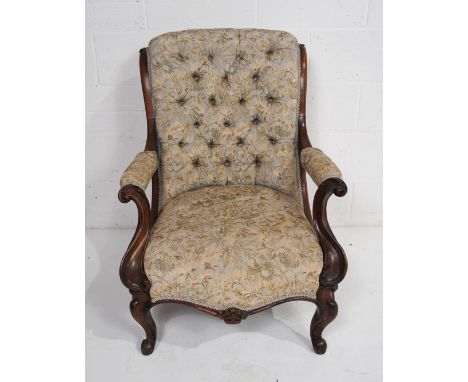 A Victorian upholstered armchair, with button-back detailing and carved decoration, raised on cabriole legs