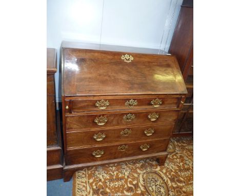 An early 19th c. Mahogany Bureau, the slope opening to reveal an interior with seven drawers and five recesses and having a b
