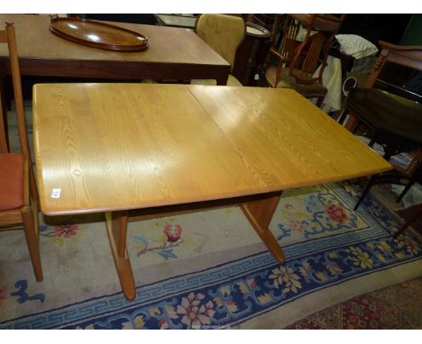 An Ercol Windsor light Elm Dining Table standing on a pair of supports, each with a circular aperture, the top 59" long with 
