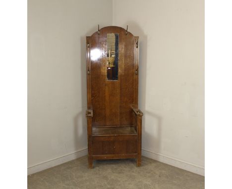 A 1930's Art Deco oak hall stand, the arched back with oblong mirror, embossed decoration and an arrangement of six hooks, ov