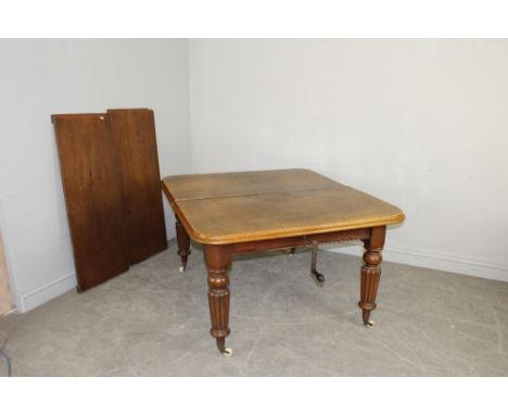 A Victorian mahogany wind-out extending dining table with moulded top on turned and reeded legs with brass caps and ceramic c