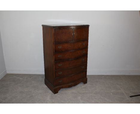 An early 20th century figured walnut tallboy chest, serpentine fronted with two cupboard doors over five drawers, on bracket 