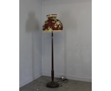 A mahogany standard lamp, with turned column, disk base and turned feet. Floral tasseled material shade. 155cm (to fitting)