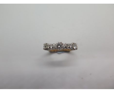 A diamond dress ring in yellow colour metal comprising of a row of round brilliant cut diamonds featuring three larger round 