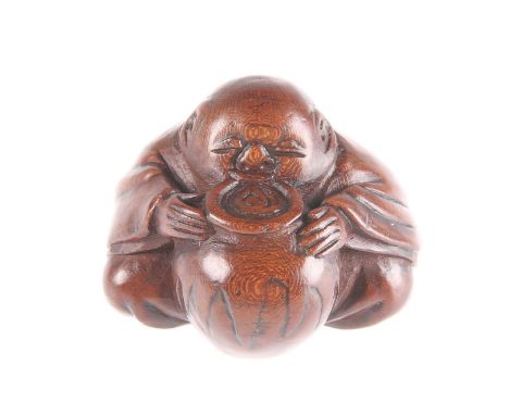 A JAPANESE WOODEN NETSUKE depicting a Shojo Sea Spirit sat drinking from a jar of sake, signed to base. 3.5cm highGood condit