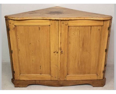 A 19TH CENTURY CAPE YELLOWWOOD CORNER DRESSER, the moulded serpentine top above two panelled doors enclosing a shelf, standin