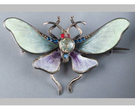 A WHITE METAL, PASTE AND ENAMEL BUTTERFLY BROOCH, the wings in green and purple enamel, decorated in blue and red stones, 3.8
