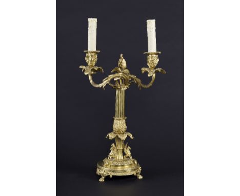 A gilt metal twin-branch table lamp with scrolling acanthus leaf arms, oak leaf cast sconces and drip pans on a reeded column