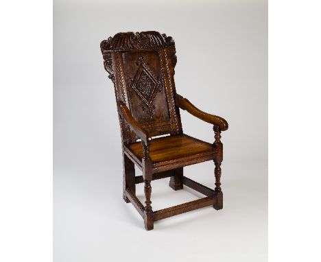 A late 17th Century fruitwood and elm panel back armchair, with scroll and leaf cresting above a lozenge carved panel, Leeds 