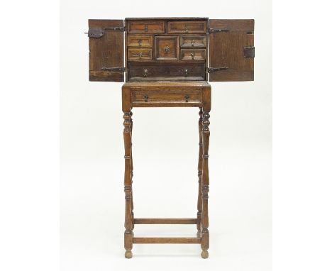 A 17th Century oak spice cupboard, the panel doors enclosing drawers, on later stand, 38cm wide