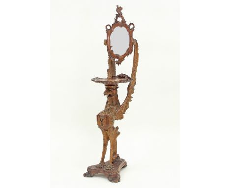 A Venetian carved walnut pedestal of grotesque winged beast form, surmounted by a swing frame mirror above a tray of scallop 