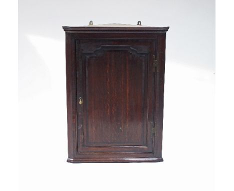 A George III oak corner cupboard, with dentil cornice above a fielded panel door, 109cm high