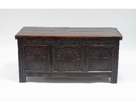 An 18th Century oak coffer, the planked top over a triple panel front with carved arches on block feet, 127cm wide