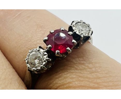 A three stone ruby and diamond ring. The central ruby is a round mixed cut stone, approximate diameter 4.8mm. The two diamond