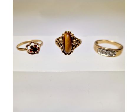 A collection of three 9ct gold dress rings. Featuring a 9ct yellow gold diamond set ring, size O; a 9ct yellow gold garnet ri