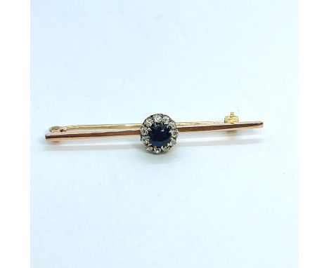 An Circa 1900s sapphire and diamond bar brooch. Featuring a central dark blue sapphire in an oval mixed cut, surrounded by a 