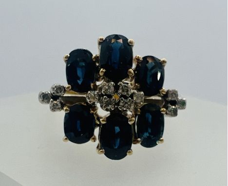 A sapphire and diamond cluster ring. Shank stamped 585. Featuring six oval mixed cut sapphires and 12 diamonds. Estimated tot