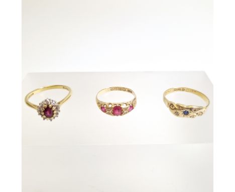 A collection of three 18ct gold rings. Featuring a ruby trilogy ring, size K1/2; a sapphire and diamond ring at fault - missi