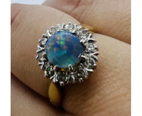 An 18ct yellow gold opal and diamond cluster ring. Featuring 10 diamonds of an estimated total weight of 0.20 carats. Size N 