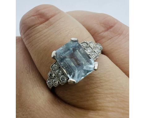 A diamond and aquamarine Art Deco style dress ring. Set in white metal marked "Plat" to the shank. The emerald cut aquamarine